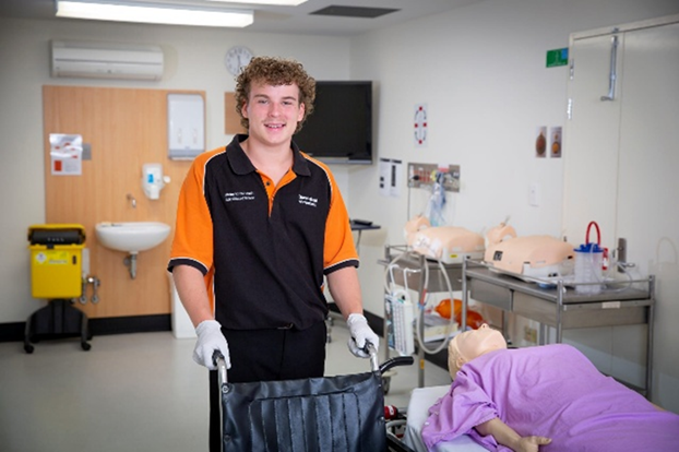 Young man behind a wheelchair in medical setting